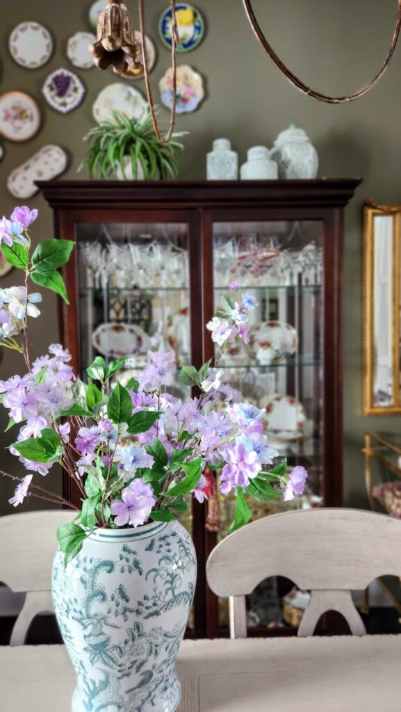 green and white ginger jar on dining room table with purple flowers in it