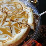 pumpkin swirl cheesecake being cut into a triangle slice