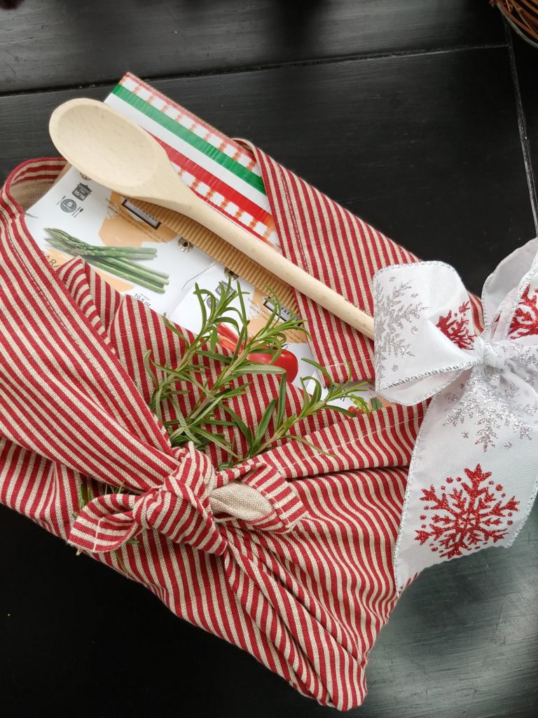christmas present wrapped with dish towel and a wooden spoon