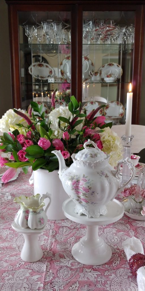A vase of flowers on a table with a tea pot