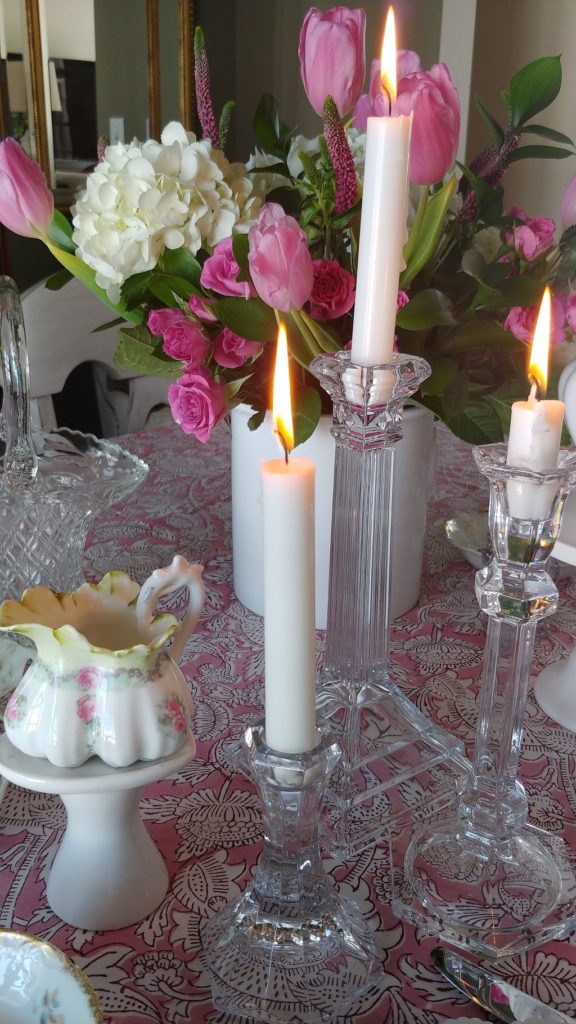 A vase of flowers on a table with crystal candle holders