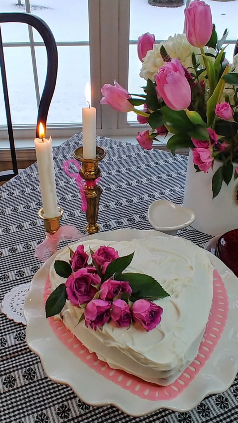 A heart-shaped cake with pink flowers on a table