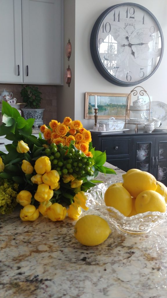 Flowers on a counter top with bowl of lemons