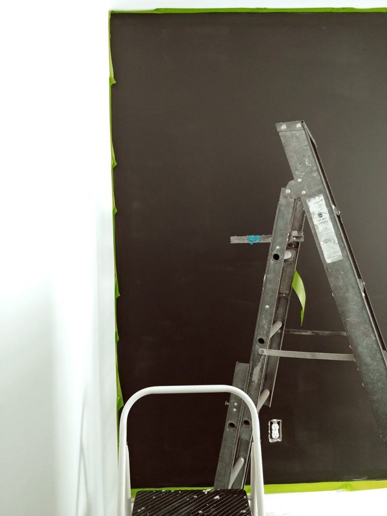 A ladder in room that is being painted