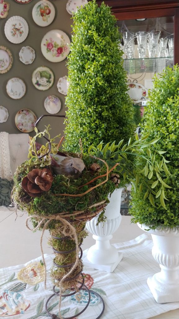 A bird cage and greenery on a table 