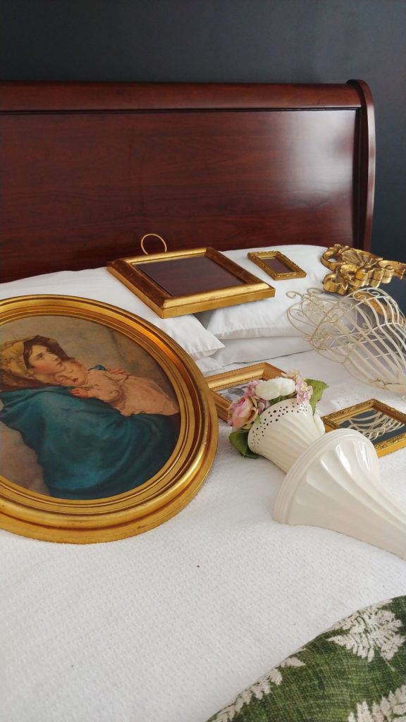 A bed with a gold picture frames getting ready to hang on the wall