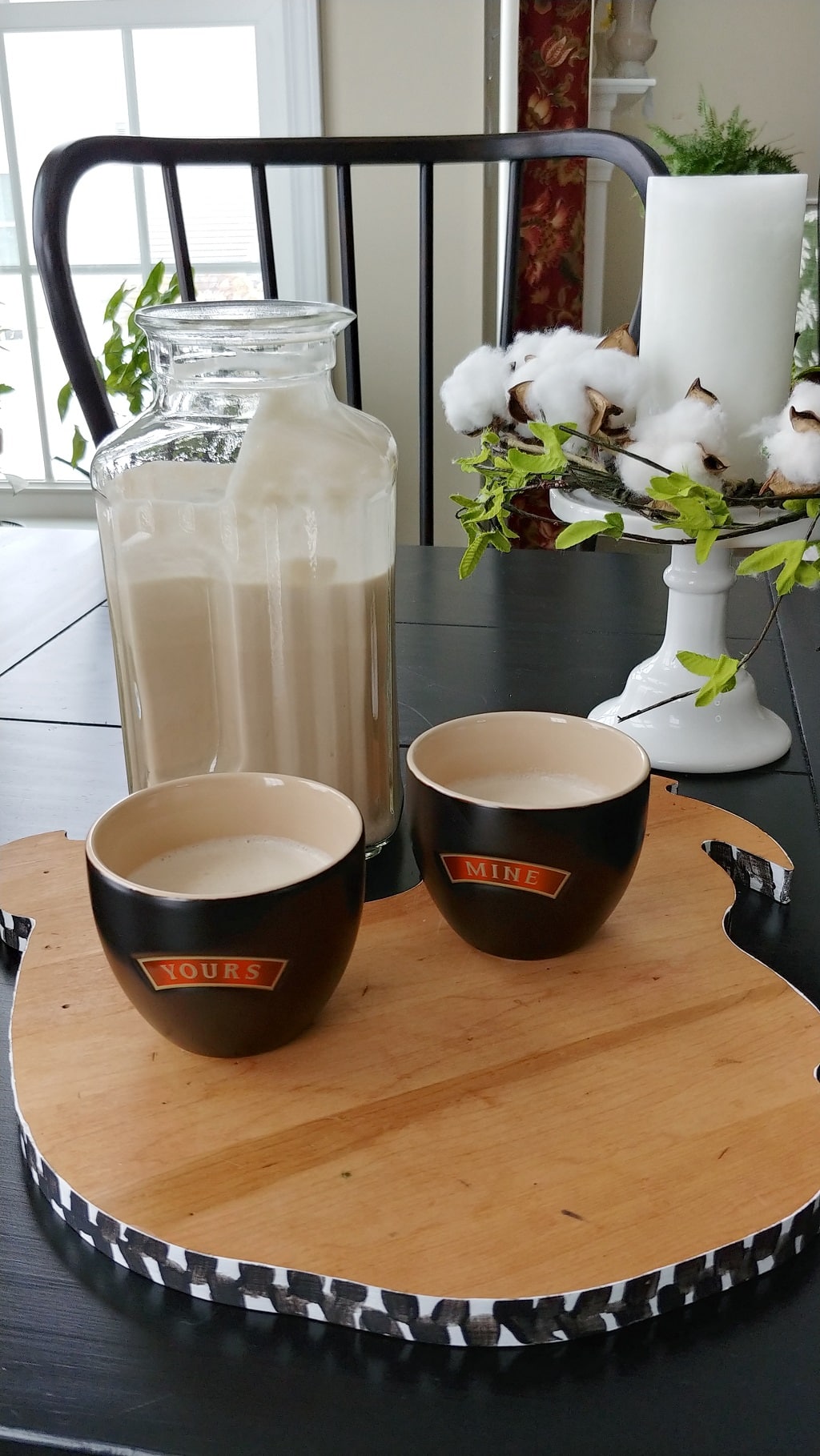 A cup of bailey's coffee and a pitcher of Irish cream on a table