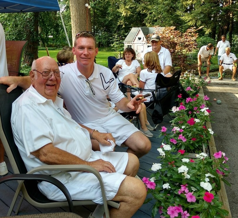 A group of people sitting watching a bocce ball game