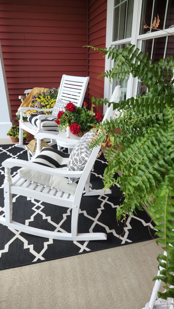 White Rocking Chairs with a green fern and black and white rug