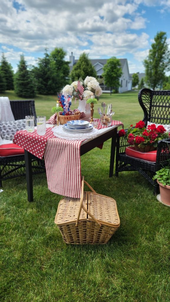 Picnic basket by table and chairs with blue sky