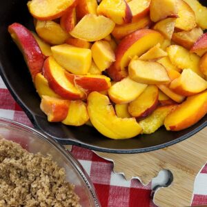 sliced peaches with crumble topping next to bowl