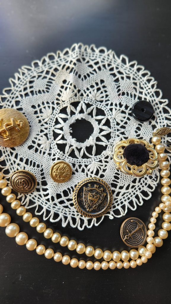 lace doilie with vintage buttons and pearls on a table