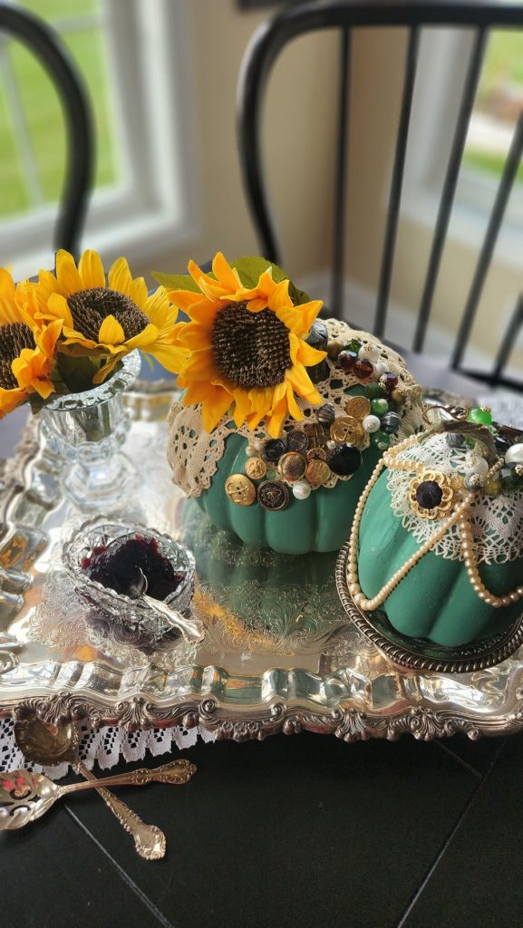 Silver tray with green painted pumpkins decorated with buttons, lace doilies and pearl necklace