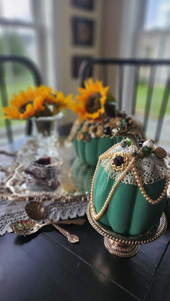 Green painted pumpkin with buttons and pearls decorating the pumpkin