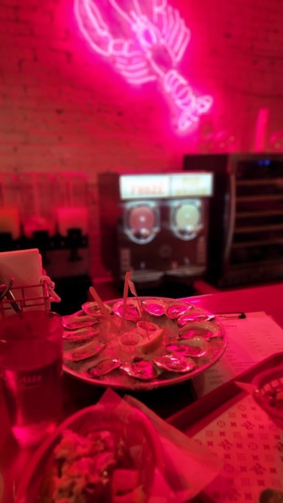 Lobster rolls and oysters in restaurant with hot pink lighting