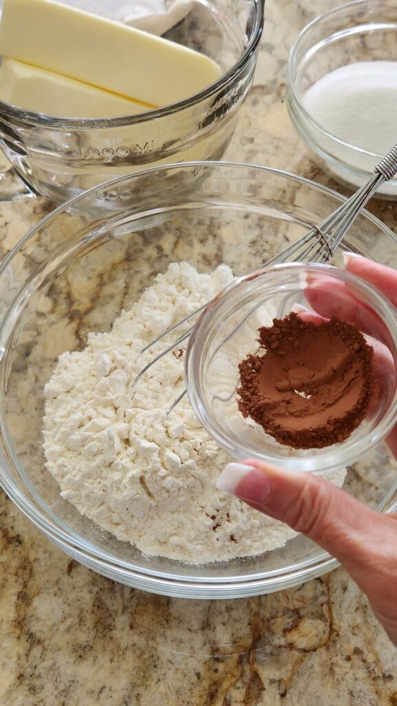 glass bowl with flour in it, adding cocoa