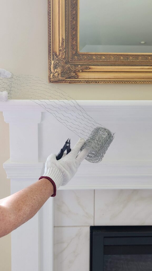 white mantel with chicken wire getting prepped for a floral swag attached