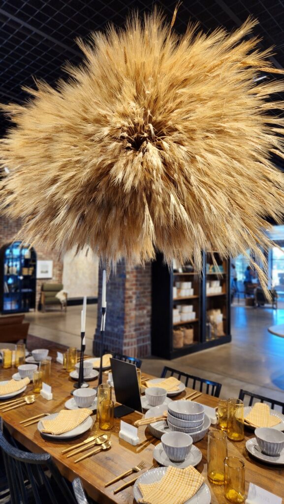 decorated table with large wheat arrangement hanging from the chandelier