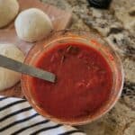 pizza sauce in glass bowl with pizza dough on side
