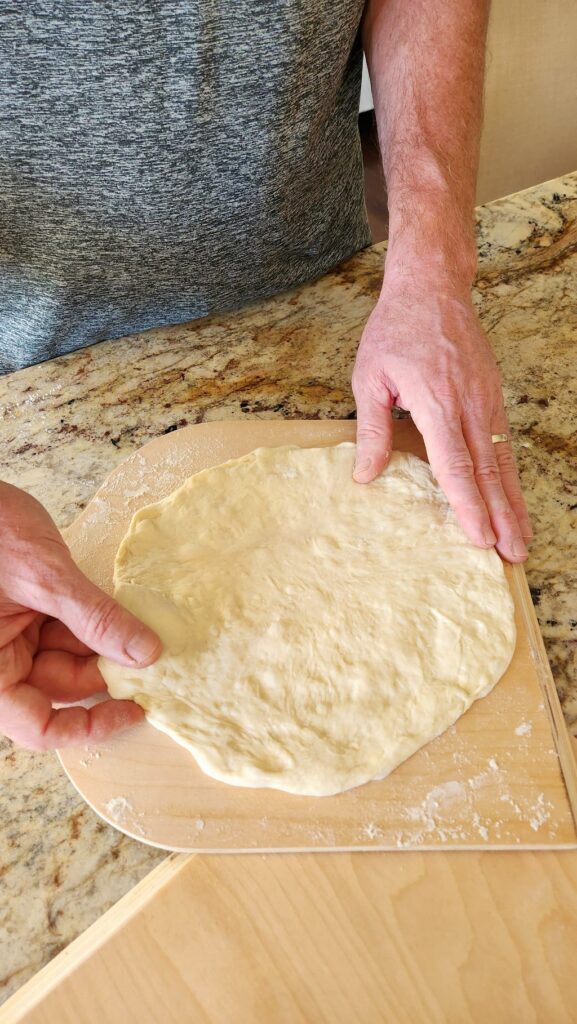 pizza dough being rolled out on counter