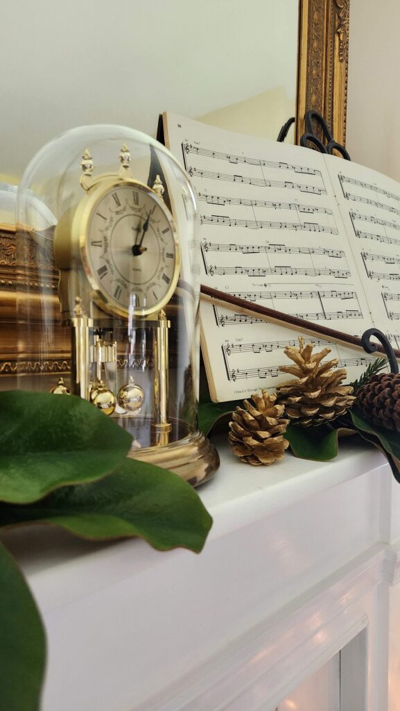 christmas mantel with swiss clock under cloche and sheet music on it