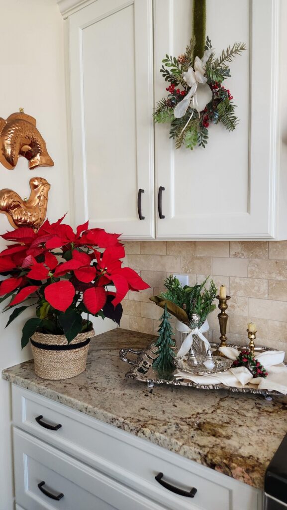 kitchen counter with red poinsettia on counter and silver tray with christmas greenery