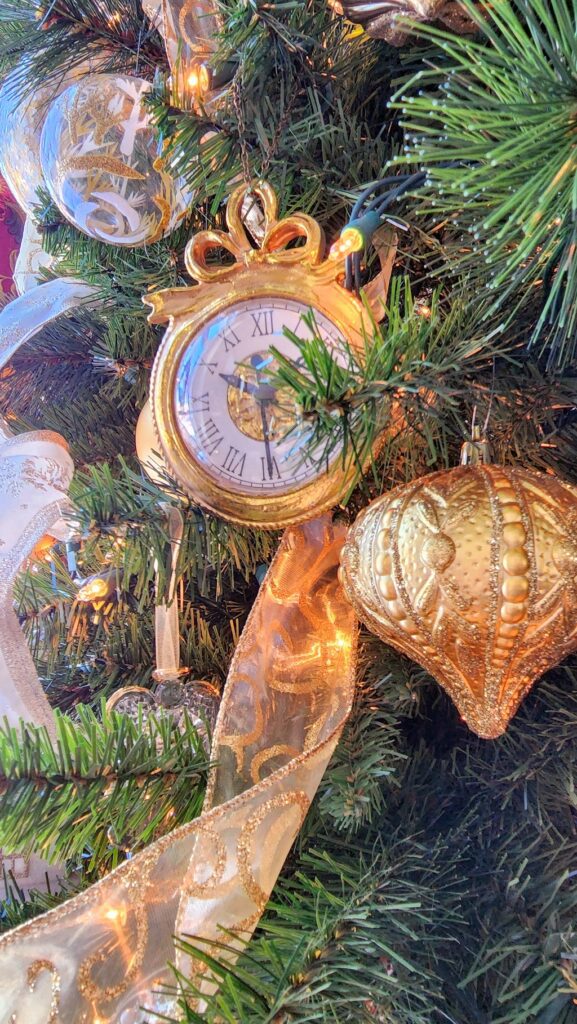 small gold clock hung on a christmas tree