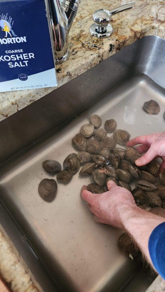 washing clams in kitchen sink with salt added