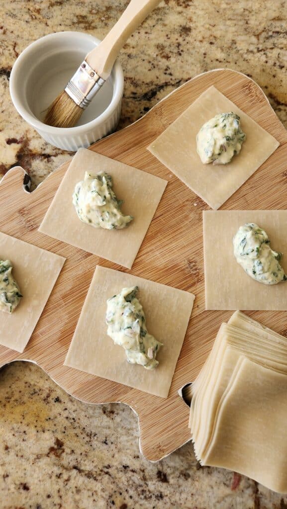 overhead view of won ton wrappers with spinach ricotta dollops on top 