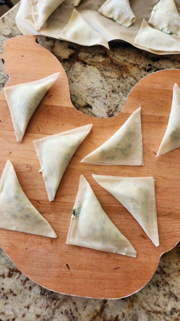 wonton wrappers with filling in triangle shape ready to be boiled