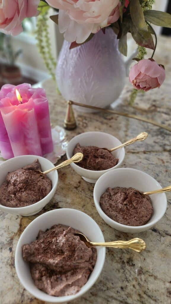 chocolate mousse in 4 cups with candle on a counter