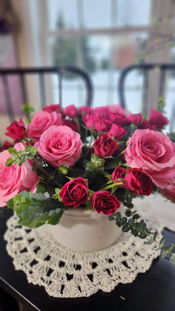 pink country roses with small spray roses in crock