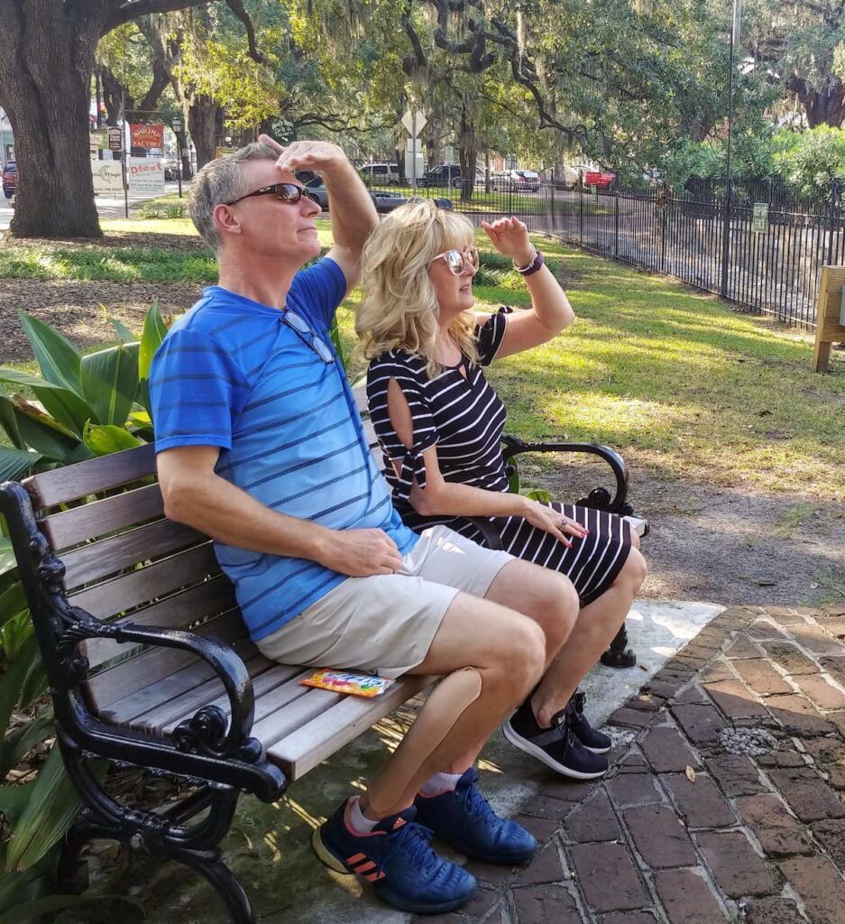 couple sitting on park bench looking to site see