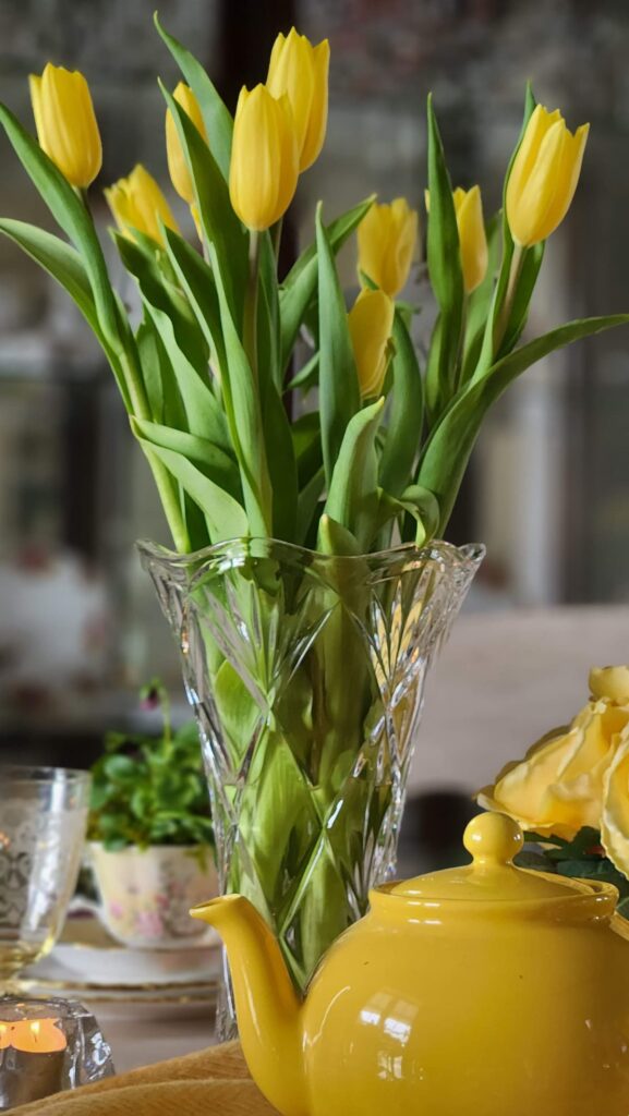 easter tablescape ideas yellow tulips in vase with yellow teapot on table