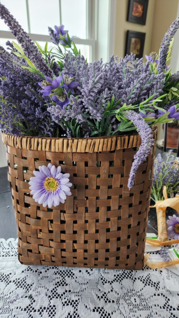 faux lavender flowers inside a woven basket with flower on front of basket