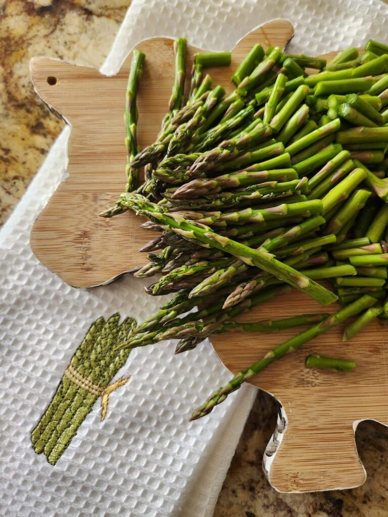 one inch asparagus cut up on wood cutting board