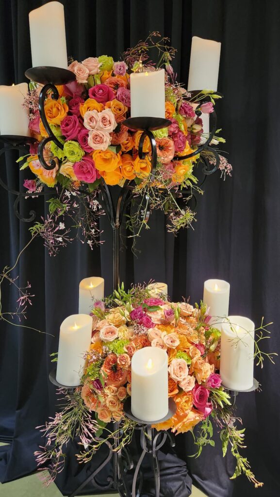 two tier floral arrangement with candles around the flowers