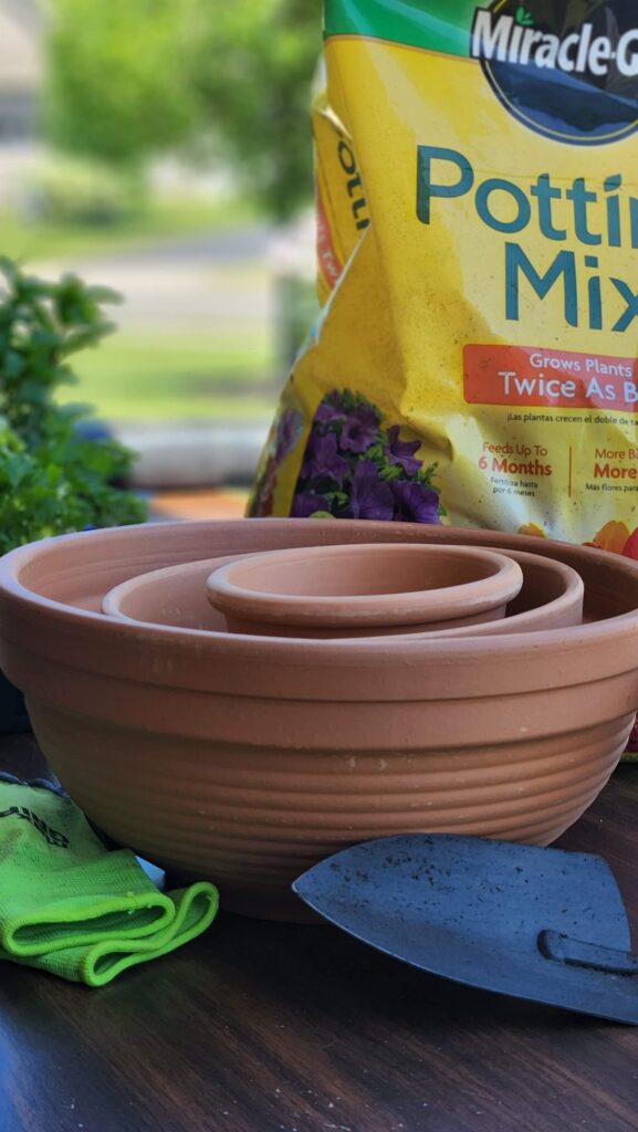 round clay pots with potting soil bag in background ready to plant herbs