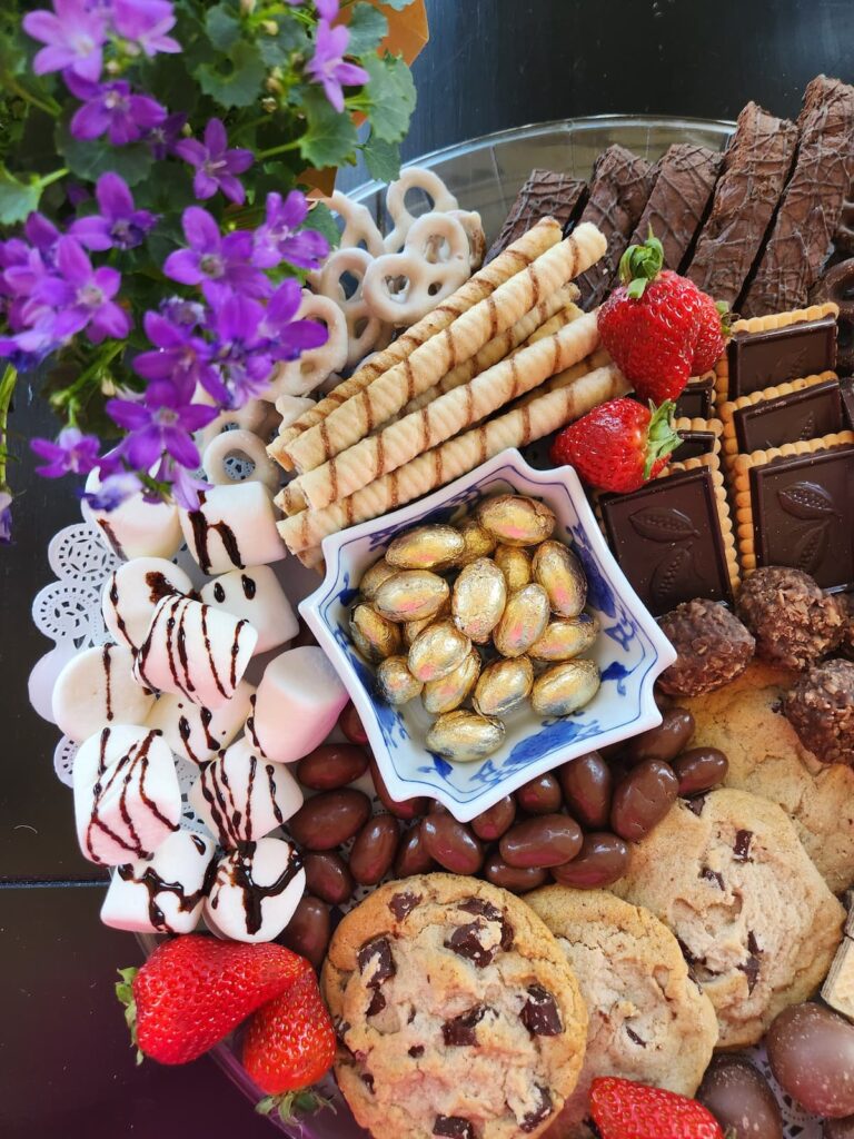overhead view of chocolate charcuterie board with purple flowers on side