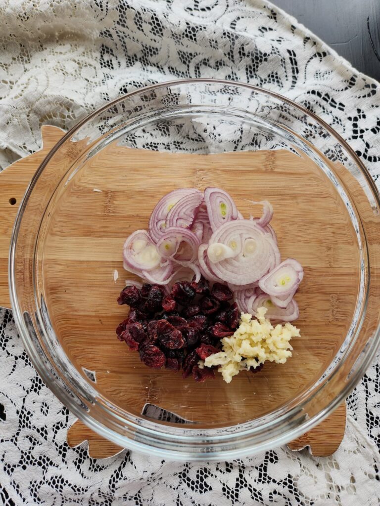 overhead view of cranberries, shallots and garlic in glass bowl