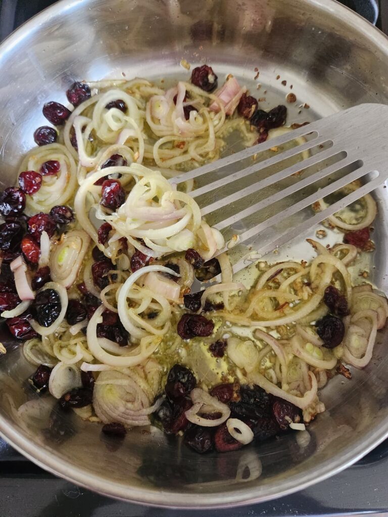 overhead view of skillet with shallots, garlic and dried cranberries being sauteed