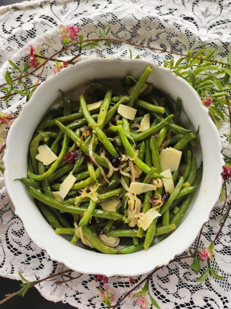 overhead of vegetarian green beans with shaved cheese and cranberries