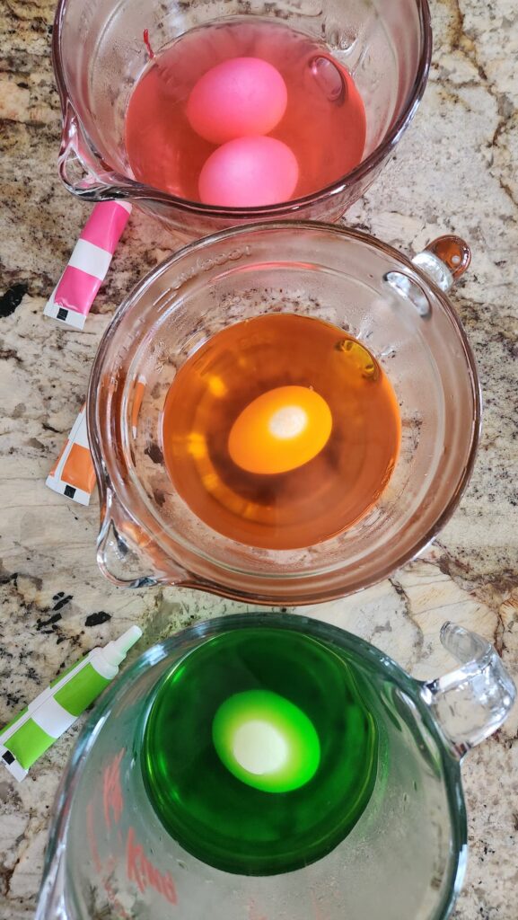 overhead of easter eggs being colored in water and white winegar