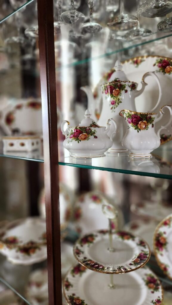 old country roses china coffee pot, creamer and sugar in china closet on glass shelf