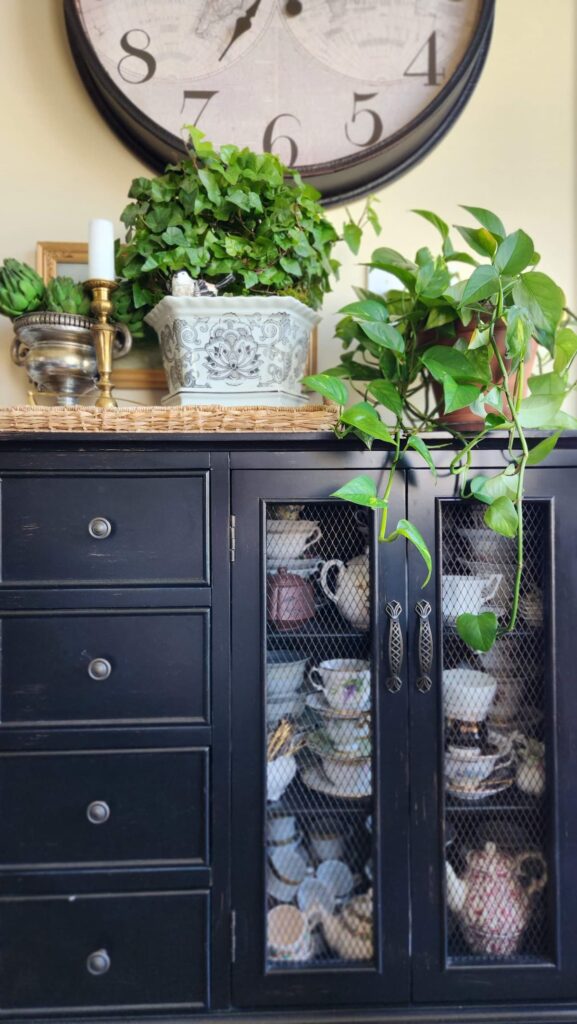 black sideboard cabinet with collection of teacups inside the mesh doors