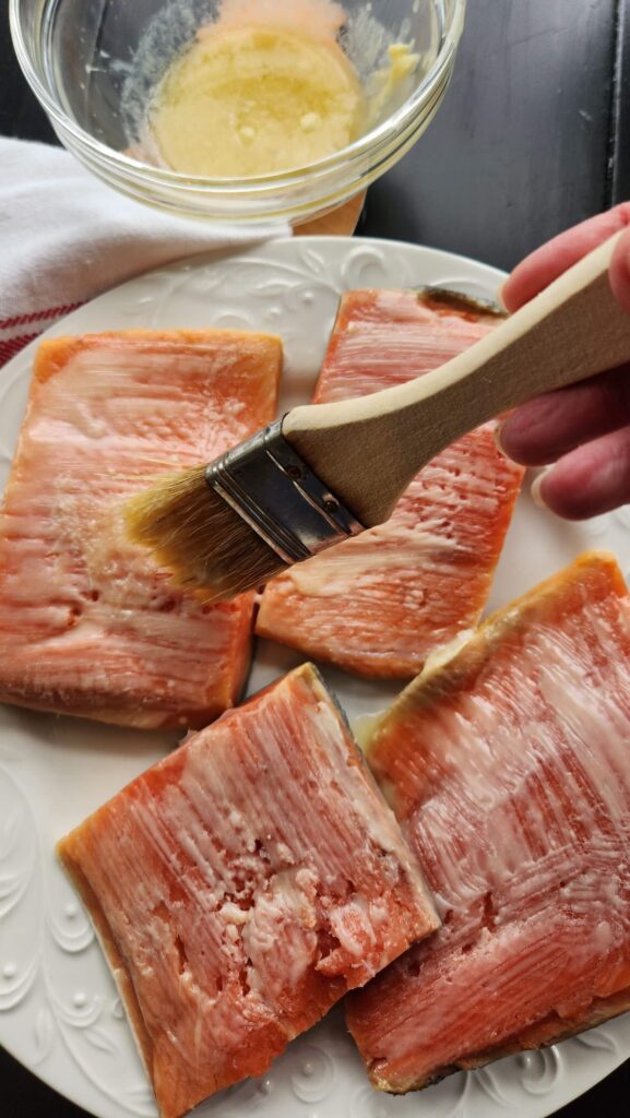 uncooked salmon with butter being brushed on top of it