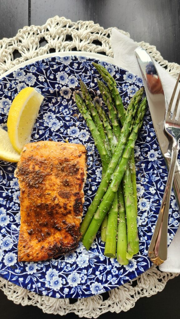 blackening salmon with asparagus on plate with lemon slices