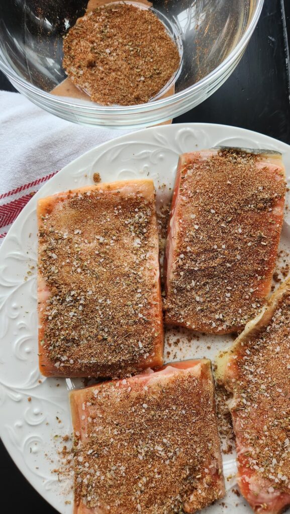 spices being added to salmon fillets