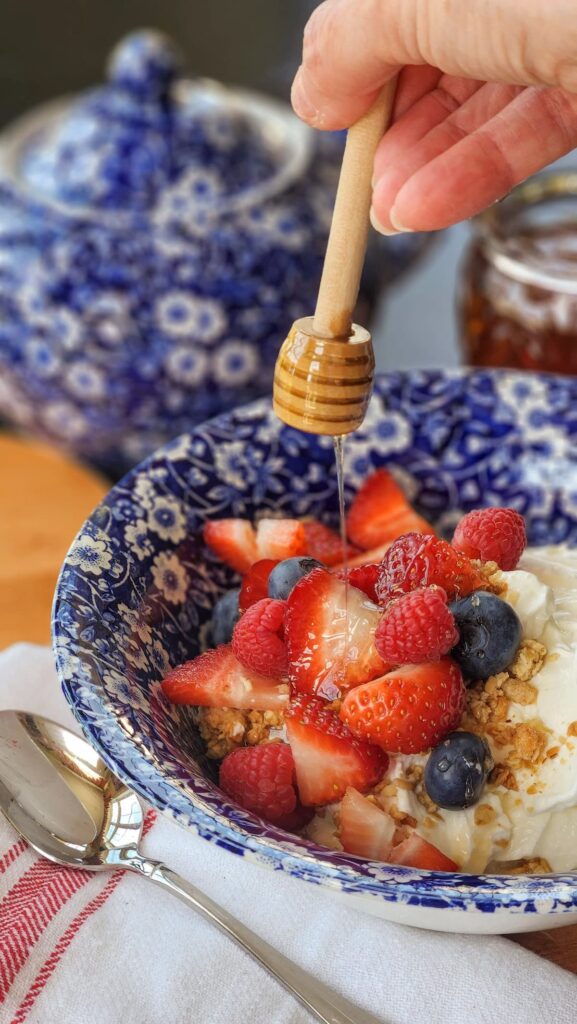 bowl of fruit with yogurt and honey being drizzled on top