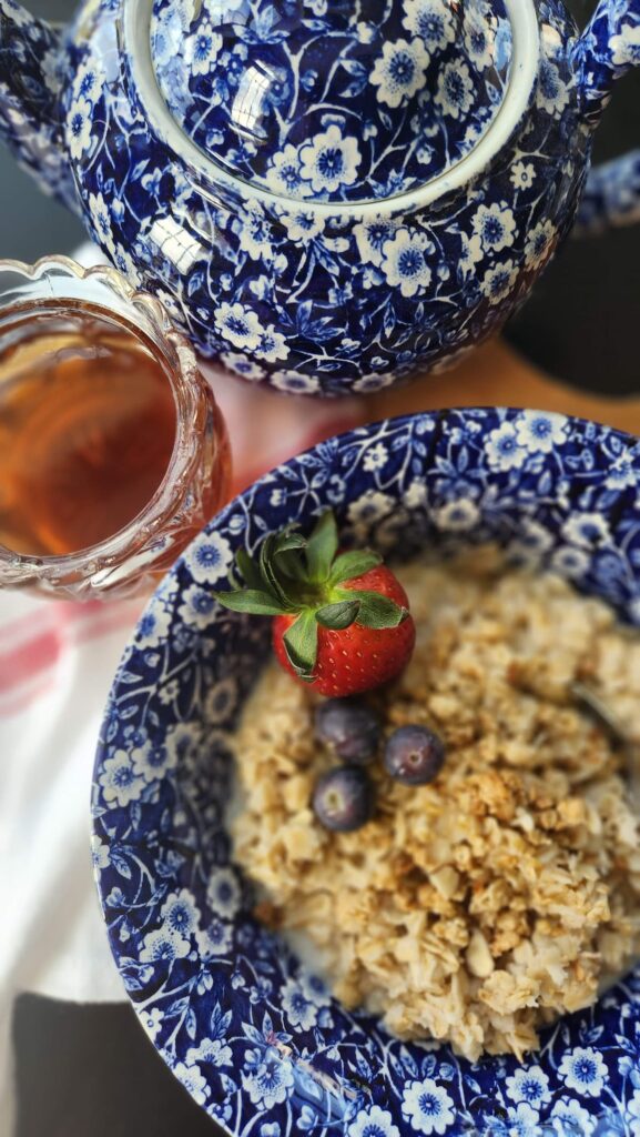 blue calico bowl filled with oatmeal, fruit and honey on side in glass jar